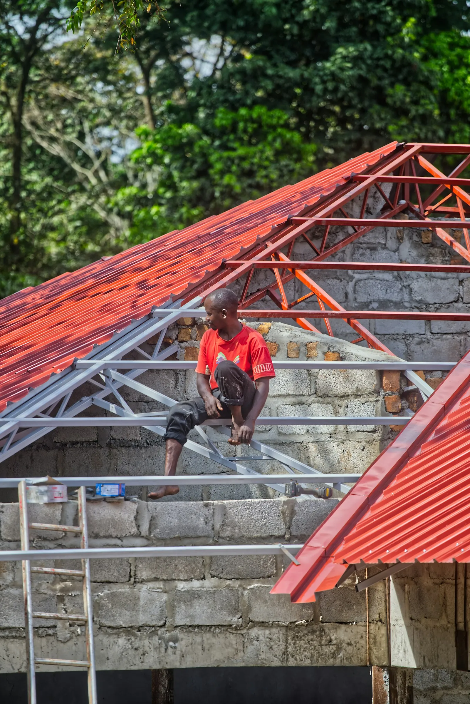 Pekerja memasang genteng metal merah baru pada rangka atap di Tegalsari